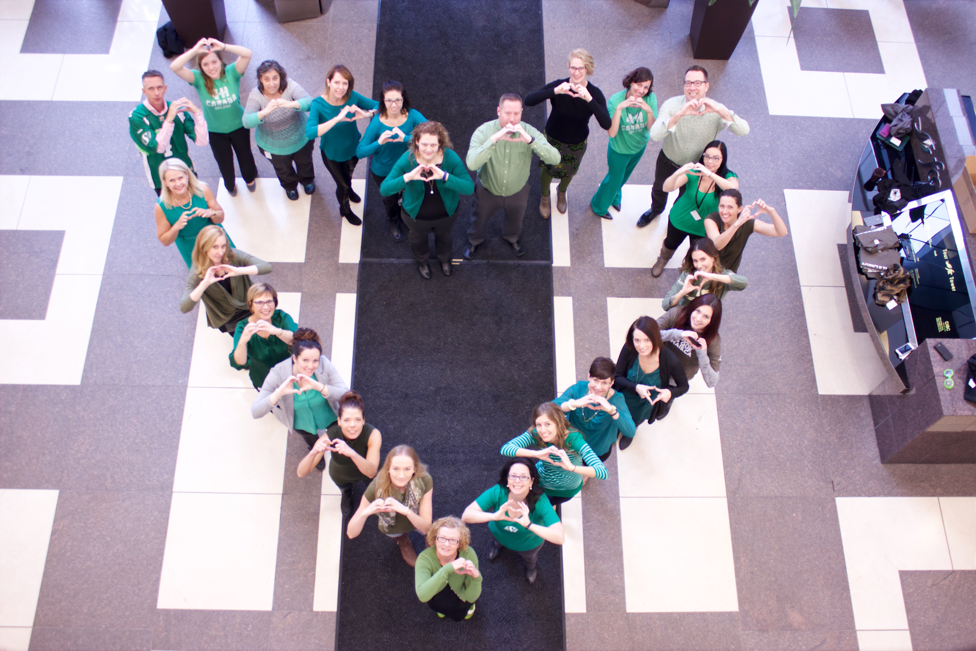 Birds Eye Shot of people standing in the shape of a heart all wearing green